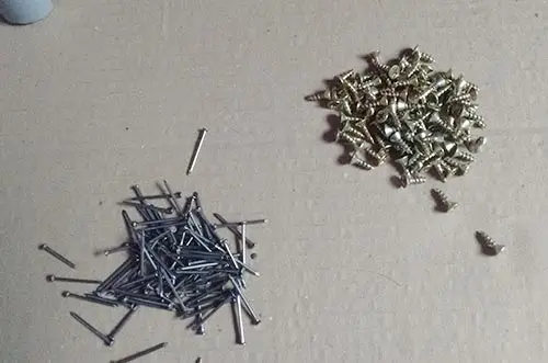Pequeños clavos y tornillos sobre un cartón